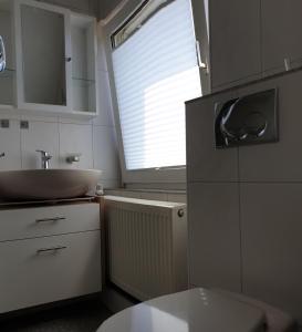 ein kleines Bad mit einem Waschbecken und einem Fenster in der Unterkunft Haus Bramland --- 2 FeWo's --- EG 60qm und OG 55qm in Haselünne