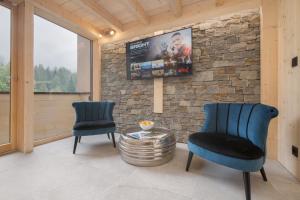 a living room with two chairs and a tv on a stone wall at Résidence Grand Roc - Bruyères 119 in Chamonix-Mont-Blanc