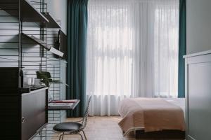 una camera da letto con un letto, una scrivania e una finestra di Supernova Hotel a Rotterdam