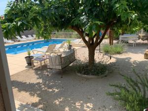 einen Tisch und Stühle unter einem Baum neben einem Pool in der Unterkunft Appartement Salvaterra in Sauveterre