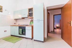 une cuisine avec des placards blancs et un tapis vert dans l'établissement MARY HOUSE, à Nuoro