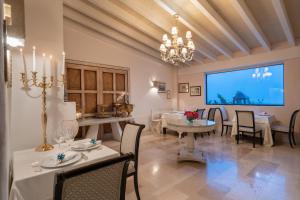 un comedor con mesas y sillas blancas y una pantalla grande en La Locanda Del Carrubo, en Mattinata