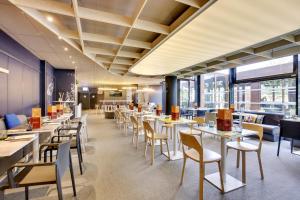 a restaurant with tables and chairs and windows at ibis Styles Paris Charles de Gaulle Airport in Roissy-en-France