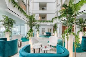 a lobby with white chairs and plants at Ivi Mare - Designed for Adults by Louis Hotels in Paphos