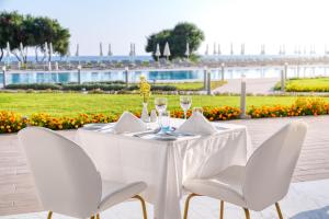 a table with two chairs and wine glasses at Ivi Mare - Designed for Adults by Louis Hotels in Paphos