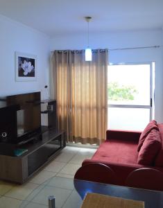 sala de estar con sofá rojo y ventana grande en Apartamento de dois quartos em Ponta Negra - Excelente Localização, en Natal