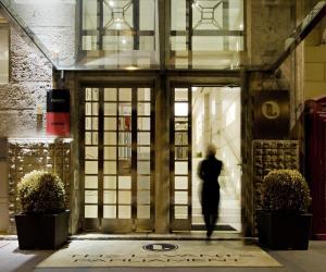 una mujer camina por la puerta de un edificio en The Levante Parliament A Design Hotel en Viena