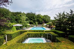 a swimming pool in a garden with bushes at Sporthotel Bruurs in Baarle-Nassau +17 photos