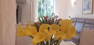 a vase of yellow flowers sitting on a table at Karina House-check in H 24 in Como