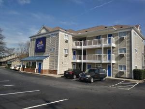 a large apartment building with a car parked in a parking lot at InTown Suites Extended Stay Greenville SC - Wade Hampton in Greenville