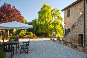 a patio with tables and an umbrella next to a building at Antica Fattoria del Colle in Deruta