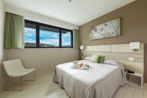 a bedroom with a bed and a chair and a window at Hotel Cristina in Naples