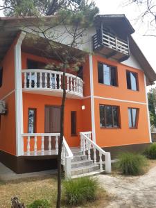 an orange house with a white balcony and stairs at Villa Shekvetili in Shekhvetili
