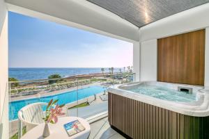 a tub in a room with a view of the ocean at Ivi Mare - Designed for Adults by Louis Hotels in Paphos