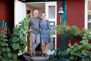 un hombre y una mujer parados en la puerta de una casa en Pension Holmegaard en Sandvig