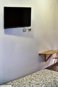 TV de pantalla plana colgada en una pared blanca en B&B Sicily, en Porto Empedocle