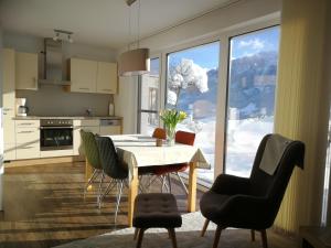 kuchnia ze stołem i krzesłami oraz dużym oknem w obiekcie Birnbacher-appartement w mieście Sankt Veit im Pongau