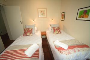 two beds in a room with white sheets at Kairos Lodge in Hout Bay