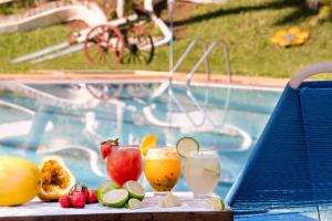 a table with two drinks and fruit on it next to a pool at Camping Valle das Aguas in Socorro