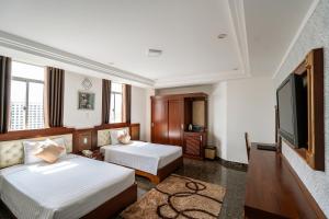 a hotel room with two beds and a flat screen tv at Duc Long Gia Lai Hotels & Apartment in Pleiku