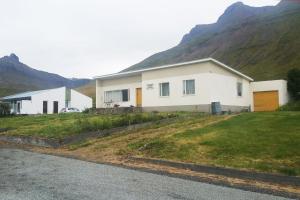 a white house with mountains in the background at House in the Westfjords in Súðavík