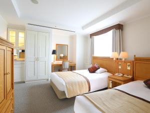 ein Hotelzimmer mit 2 Betten und einem Fenster in der Unterkunft Wishton Hotel Yukari in Sakura