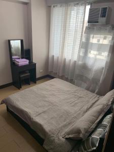 a bedroom with a large bed and a window at Cubao ManhattanHeights Unit 11A Tower B, 2BR in Manila