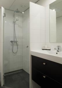 een witte badkamer met een douche en een wastafel bij Parkhotel De Bosrand in Ede