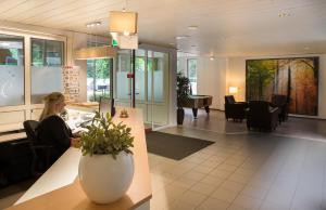 a woman sitting at a table in a lobby at Parkhotel De Bosrand in Ede