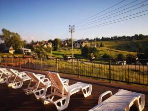 a row of white chairs sitting on a deck at Willa Modra in Bukowina Tatrzańska