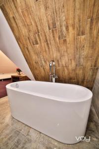 y baño con bañera blanca y pared de madera. en Willa & DOM-BLACH, en Szaflary