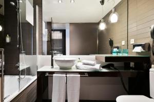 een badkamer met een wastafel, een bad en een douche bij Hotel Barcelona Condal Mar Affiliated by Meliá in Barcelona