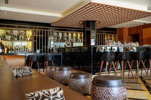 a bar with leather stools and a bar counter at Grande Real Villa Itália Hotel & Spa in Cascais