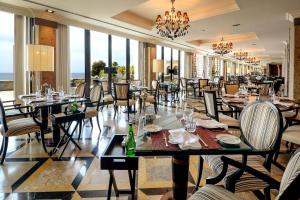 a restaurant with tables and chairs and a chandelier at Grande Real Villa Itália Hotel & Spa in Cascais