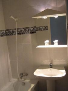 a white bathroom with a sink and a mirror at La Fontaine in Vidauban
