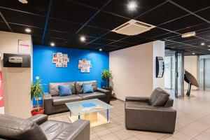 una sala de espera con sofás y una pared azul en Appart'City Classic Montelimar, en Montélimar