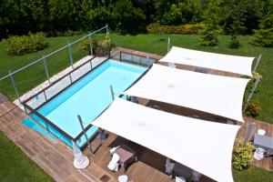 an overhead view of a swimming pool with two white umbrellas at Chiaroscuro in Belforte del Chienti