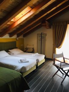 a bedroom with two beds and a chair at Hotel Nordend in Gressoney-la-Trinité