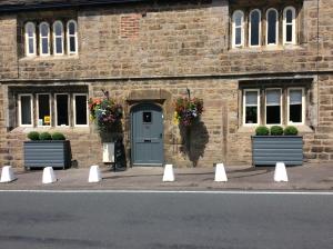 a brick building with a blue door and potted plants at Rye Flatt Bed and Breakfast in Colne