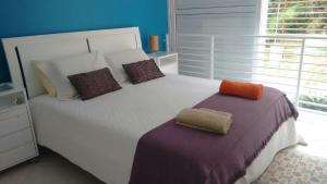 a bedroom with a large white bed with two pillows at Confortável Casa Condomínio Marbella in Angra dos Reis
