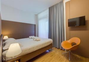 a bedroom with a bed and a chair and a television at Camplus Bononia Casa per Ferie in Bologna +62 photos