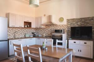 a kitchen with white cabinets and a wooden table with chairs at Casa vacanze Beach House vicino alla stazione in La Spezia