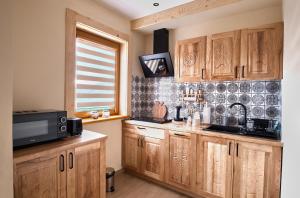 a kitchen with wooden cabinets and a microwave at Domek Lilijka in Poronin