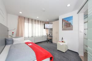 Cette chambre comprend un lit avec une couverture rouge. dans l'établissement Aalener Römerhotel aWL, à Aalen