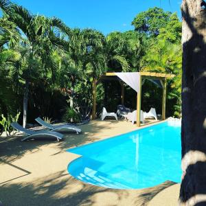 - une piscine dans un complexe avec des chaises et des arbres dans l'établissement Ti coin paradis, à Anse-Bertrand