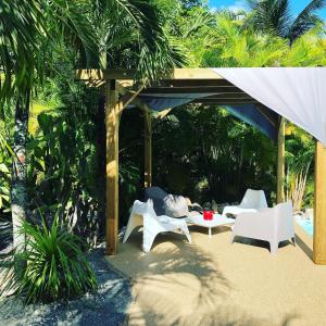 - un pavillon avec des chaises blanches et une table dans l'établissement Ti coin paradis, à Anse-Bertrand