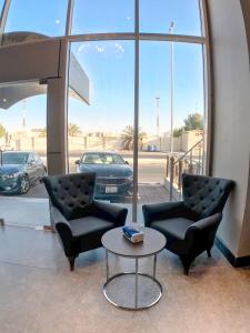 two chairs and a table in front of a car dealership at لافنت بارك للشقق المخدومة - إقتصادي in Jeddah