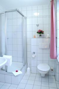 a white tiled bathroom with a toilet and a shower at Paulin Hotel Trier in Trier