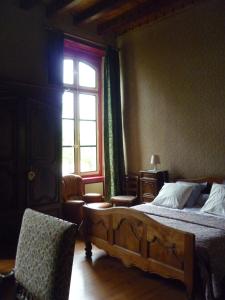 a bedroom with a bed and a window and a chair at Château de Vallègue in Vallègue