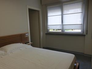 1 dormitorio con cama blanca y ventana en Residence Campo Rotondo, en Tavernerio